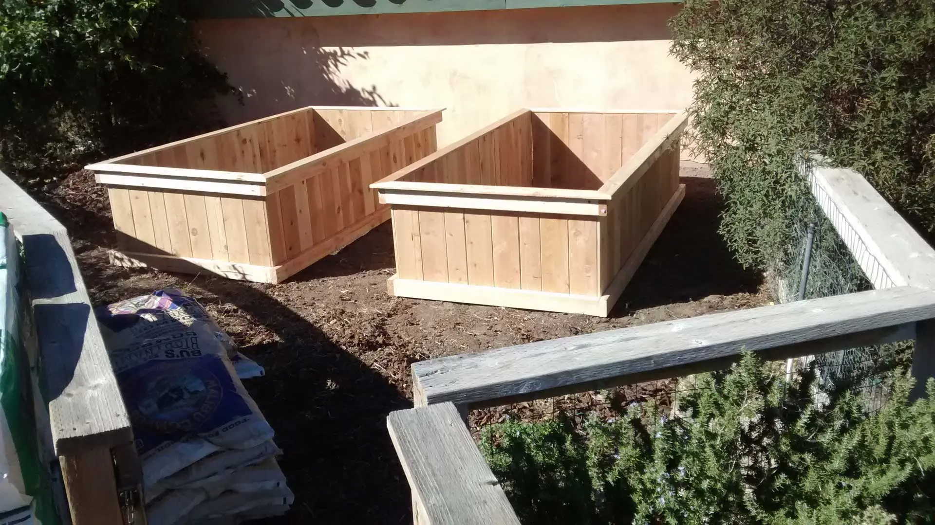 Two wooden planter boxes in a backyard.