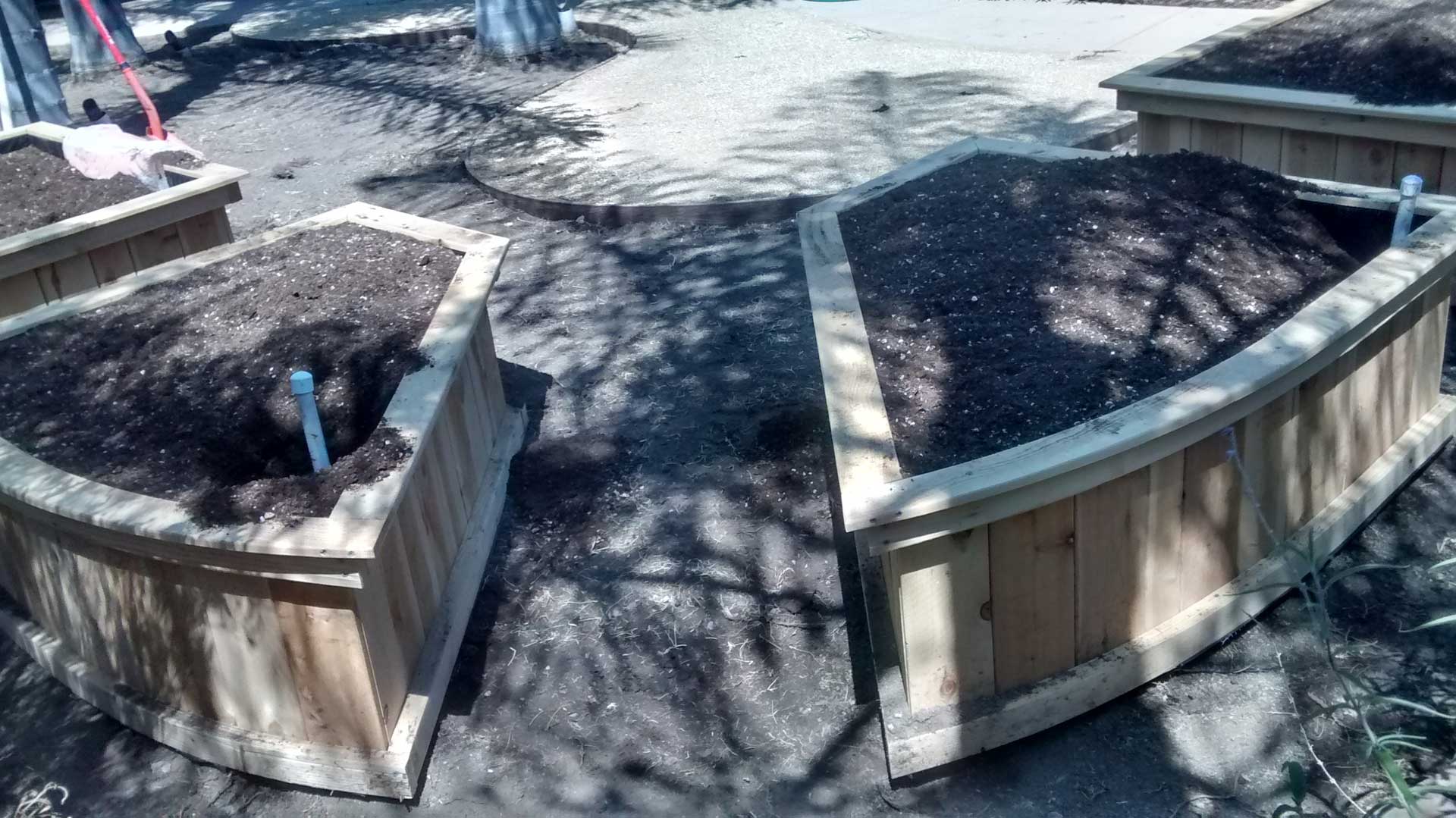 Two wooden planters with dirt in them.