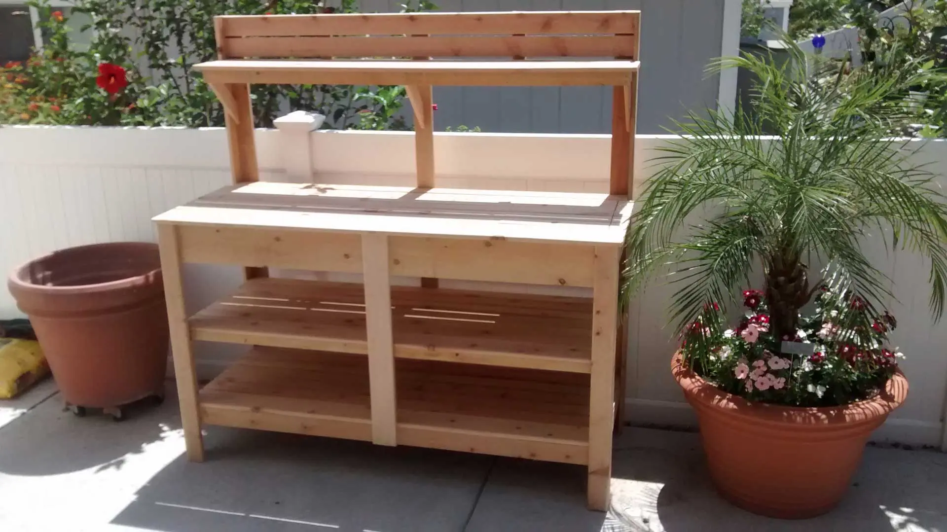 A wooden bench with two shelves and a plant.
