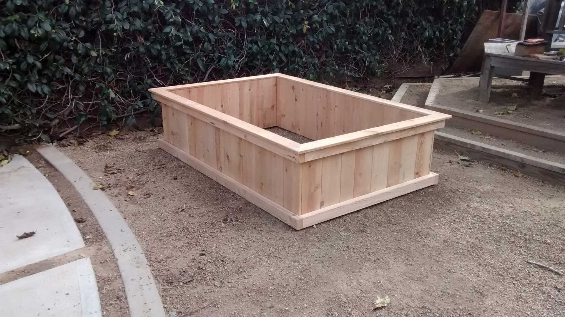 A wooden planter box sitting on the ground.