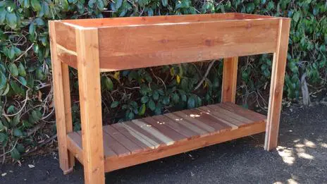 A wooden planter with a shelf on top.