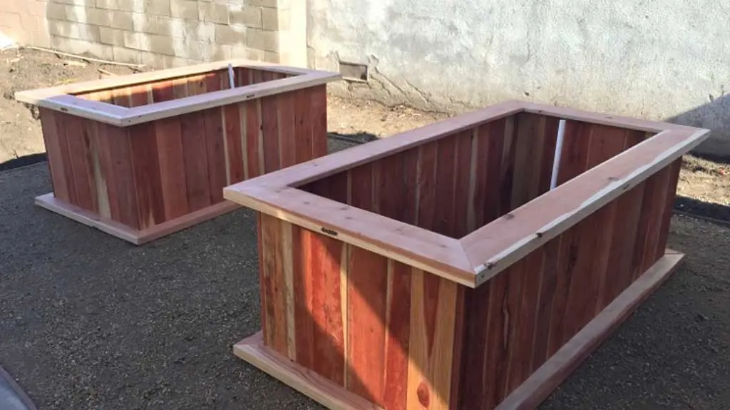 Two wooden planters sitting on the ground.