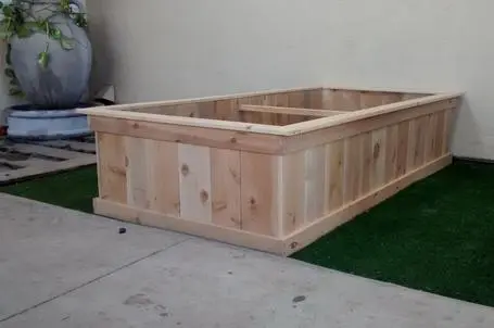 A wooden planter box sitting on a grassy area.