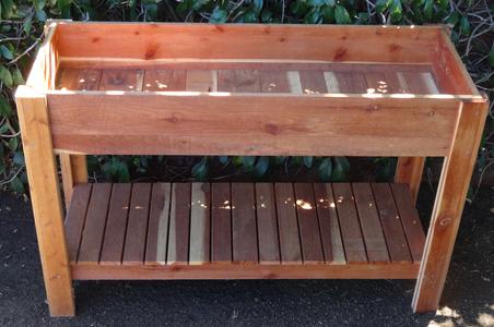 A wooden raised garden bed with a wooden shelf.