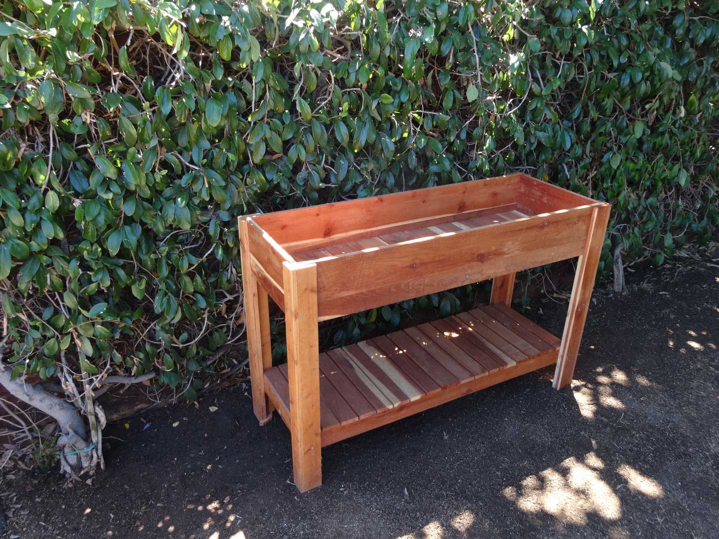 A wooden planter box sitting on top of a cement ground.