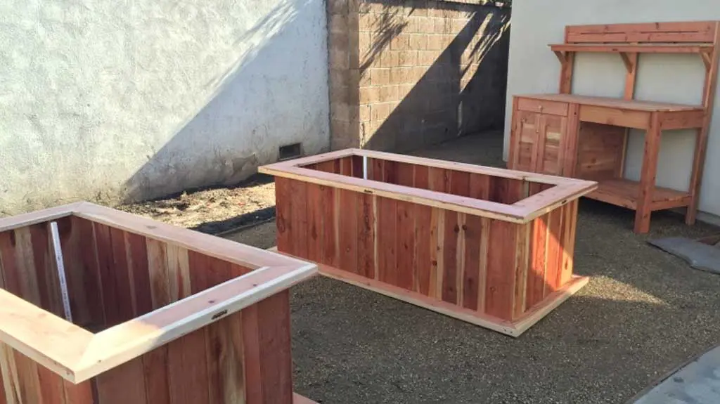 Two wooden planters in a backyard.