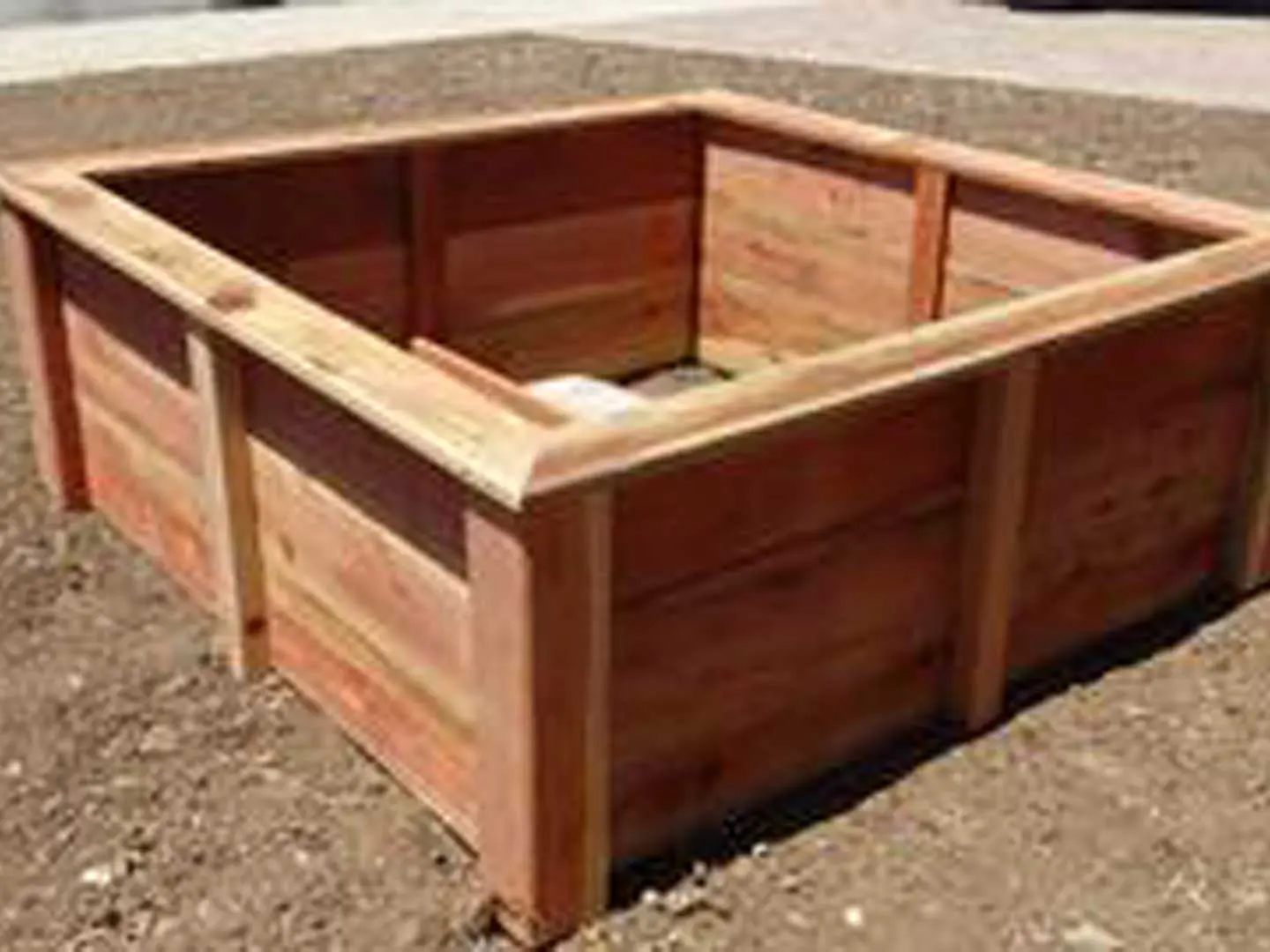 A wooden raised garden bed in the dirt.