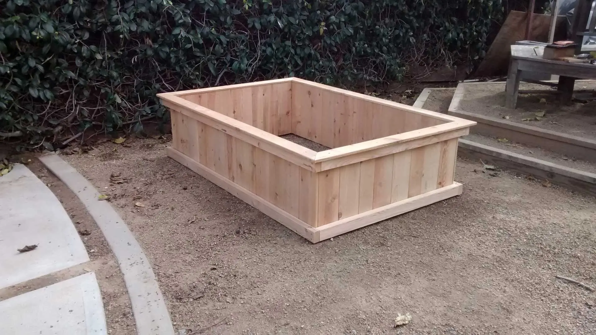 A wooden planter box sitting on the ground.