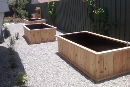A set of wooden planters in a gravel yard.