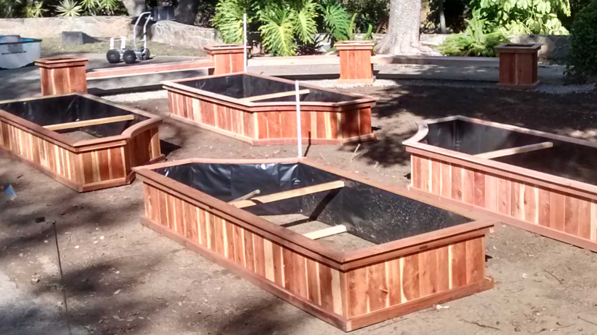A group of wooden raised garden beds in a yard.