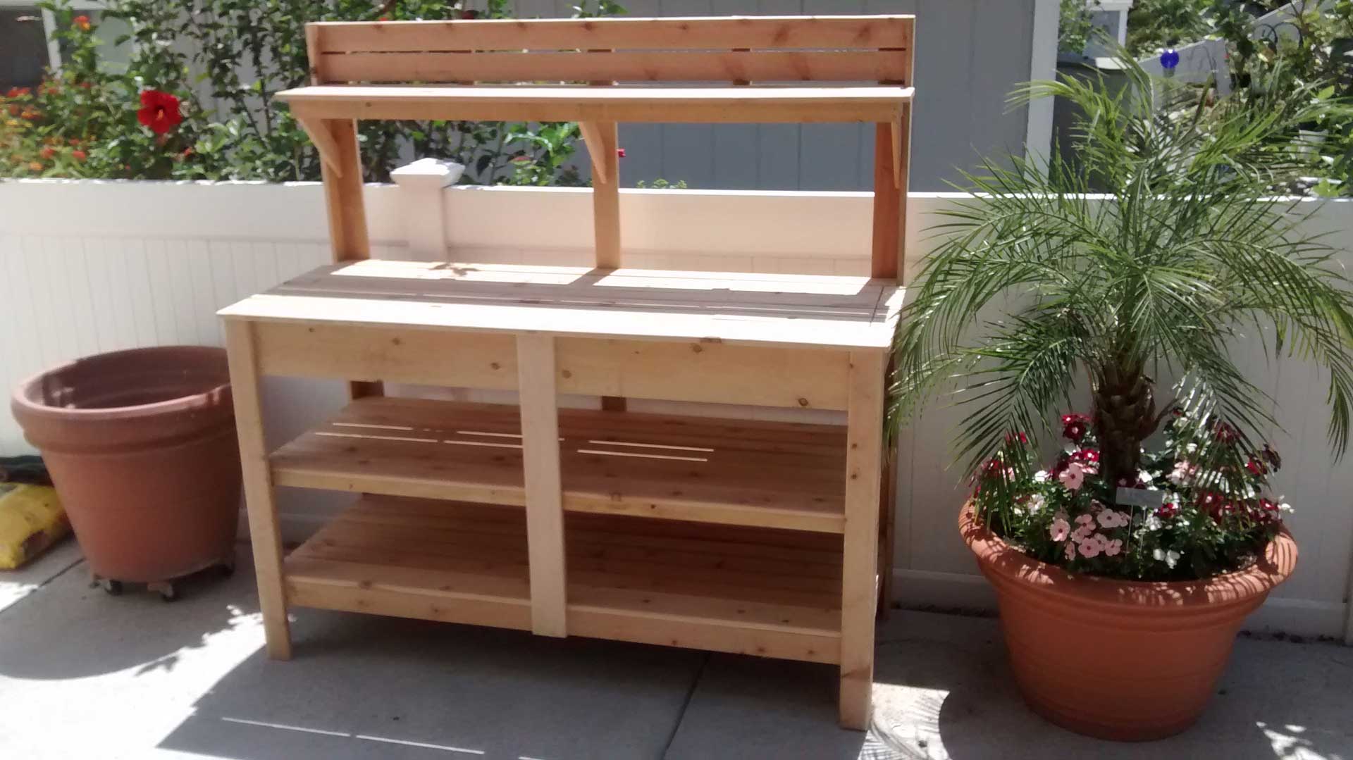 A wooden potting bench with potted plants on it.