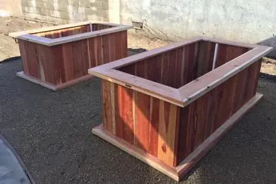 Two wooden planters sitting on the ground.
