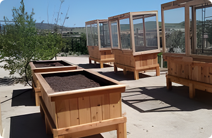 A row of wooden raised garden beds with soil in them.