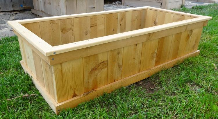 A wooden planter box on a grassy area.