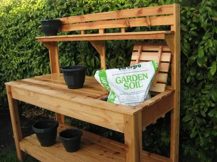 A wooden garden potting bench with pots on it.