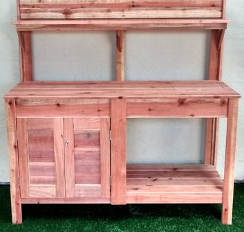 A wooden potting bench with a shelf and drawers.