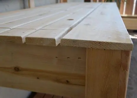 A close up of a wooden bench on a wooden deck.