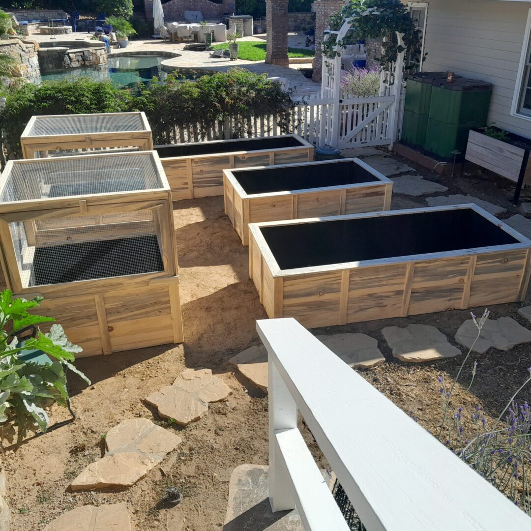 Four wooden garden beds with covers.